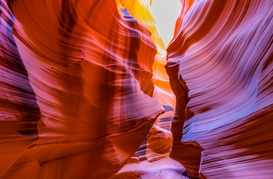 Magenta, red-orange, and gold illustration of Antelope Canyon in Arizona with gray sky on the horizon. This image represents Angela V. Fox Coaching’s athletic performance coaching services.