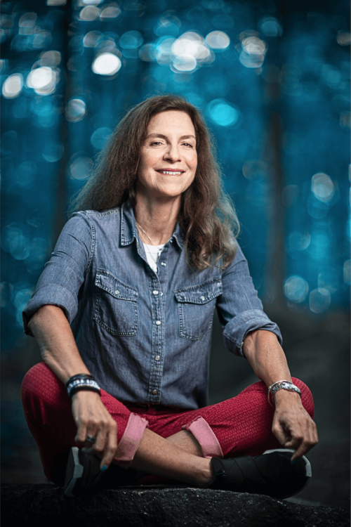 Photo of coach Angela V. Fox in a blue denim shirt and red pants, sitting on a ledge in a Charlotte, NC, park.