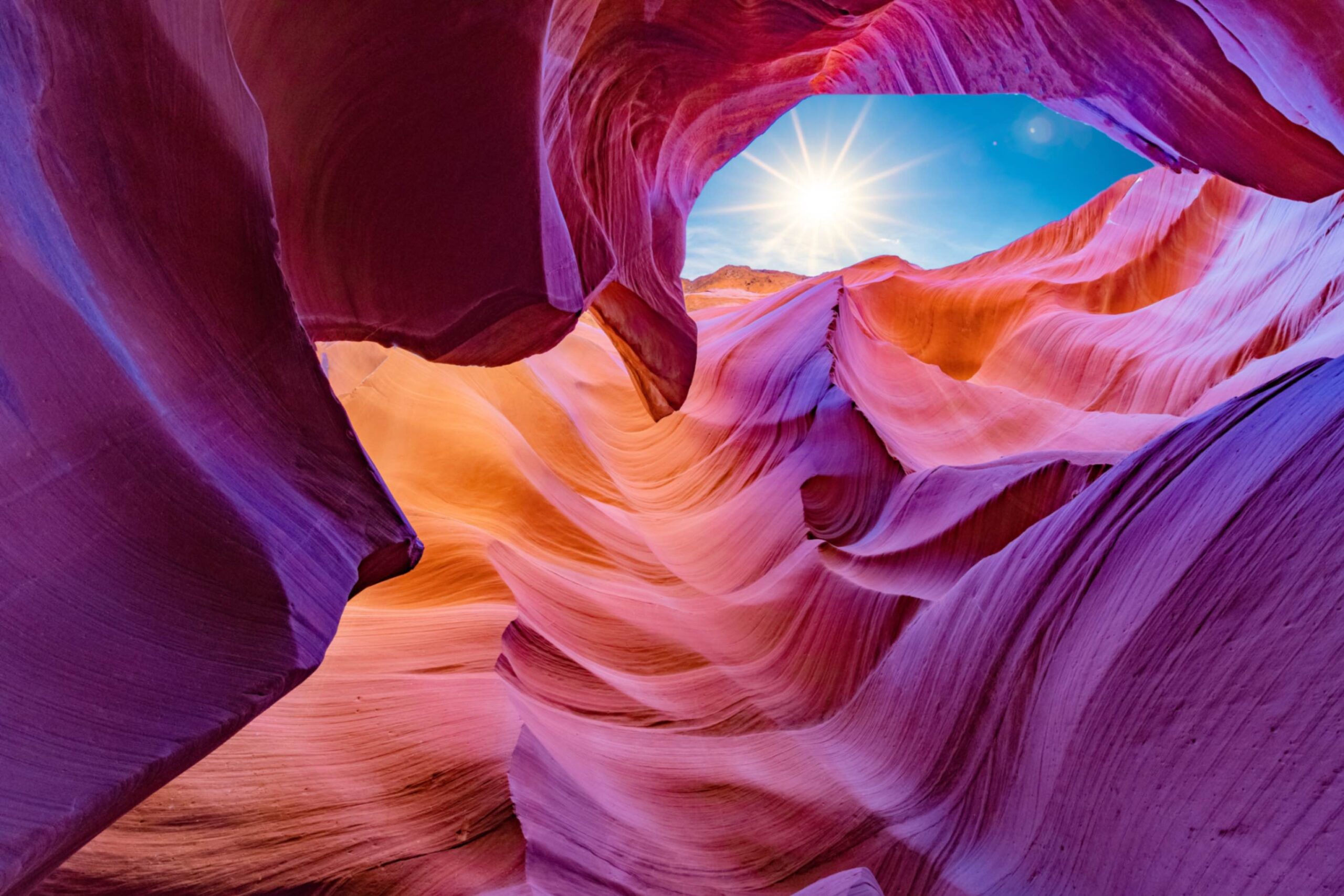 Purple, magenta, and orange illustration of Antelope Canyon in Arizona with blue sky and sun in the distance. This image represents Angela V. Fox Coaching’s executive coaching services.